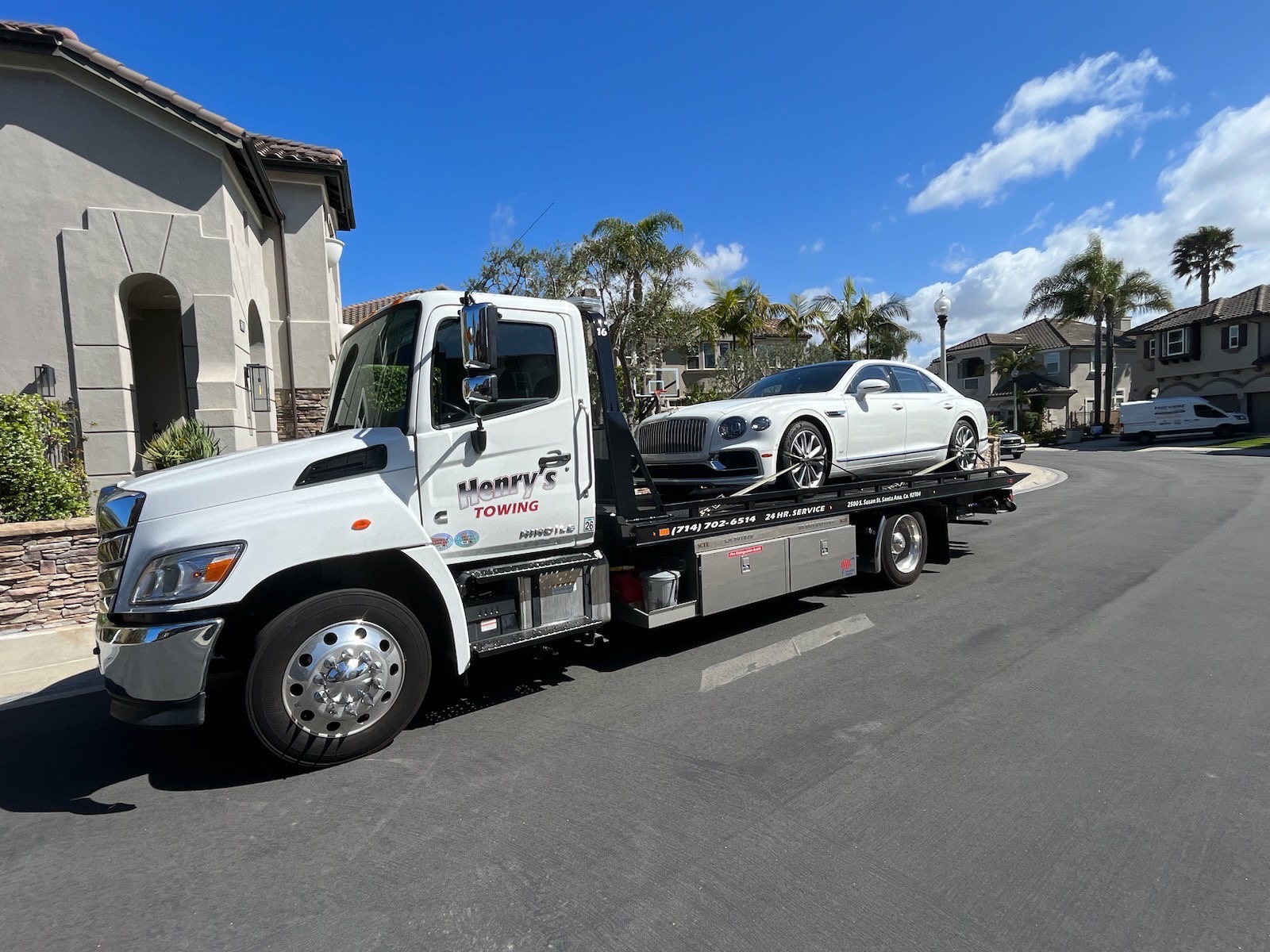Henry's Towing flatbed tow truck transporting a luxury car in Tustin, CA